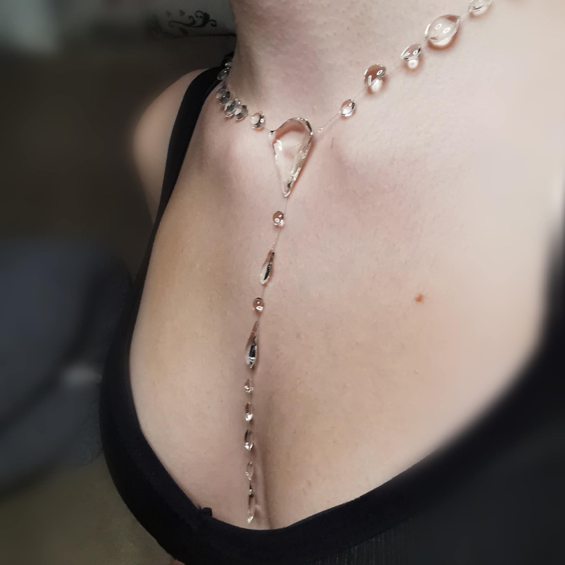 A stunning Y-shaped floating Negligee necklace featuring crystal-clear droplets that create the illusion of cascading raindrops. Designed with an elegant asymmetrical layout, this ethereal jewelry piece gracefully drapes along the collarbone and décolletage, offering a delicate, nature-inspired aesthetic. Perfect for those who appreciate minimalist, modern elegance